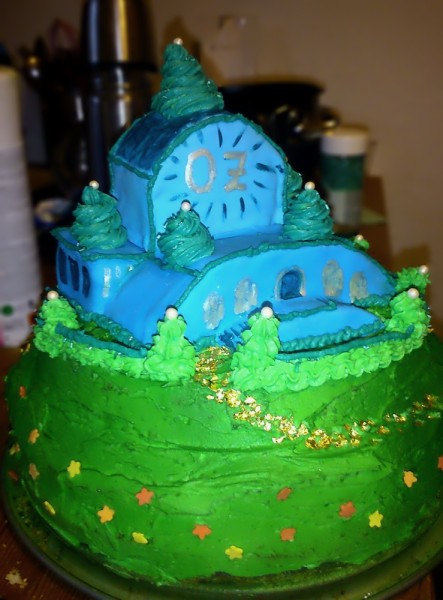 blaue Smaragdstadt auf grünem Berg mit Blumenwiese und Stadtmauer, als Torte